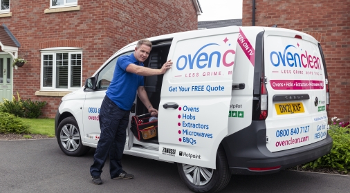 Ovenclean specialist placing tool bag inside side door of an Ovenclean van, parked outside a modern house.