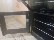 Shiny silver oven shelves inside black oven after being cleaned