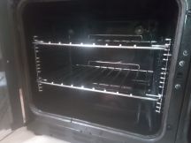 Shiny silver oven shelves inside black oven after being cleaned