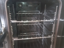 Shiny silver oven shelves inside narrow oven after being cleaned