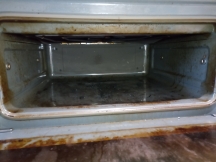 Small oven with dirty interior and door before being cleaned