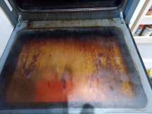 Dirty brown oven door before being cleaned