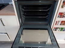 Clean grey oven interior with open door next to spice rack
